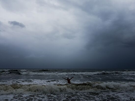 Мужчина купается в море во время шторма.