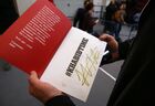 Болельщик бойца смешанного стиля, чемпиона абсолютного бойцовского чемпионата (UFC) в легком весе Хабиба Нурмагомедова держит в руках книгу с его автографом после пресс-конференции перед чемпионатом Gorilla Fighting Championship в спортивном комплексе "Чемпион" в Краснодаре. Место: Россия, Краснодар. Автор: Виталий Тимкив/РИА Новости. П/к бойца ММА Х. Нурмагомедова