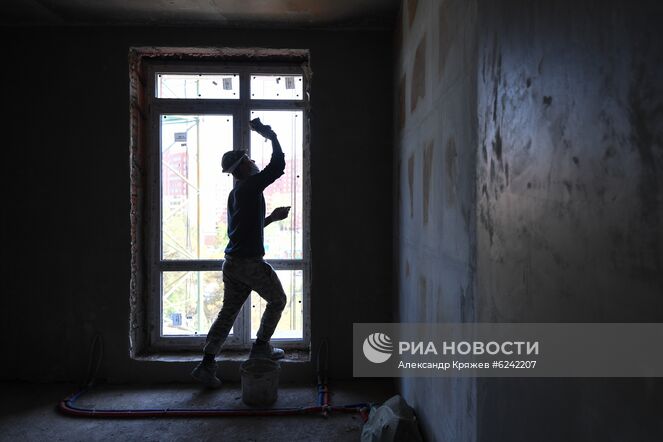 Рабочий во время отделочных работ в здании жилого комплекса "Эволюция" в микрорайоне "Стрижи" в Новосибирске. В микрорайоне проводится комплексная застройка по программе развития застроенных территорий. Место: Россия, Новосибирск. Автор: Александр Кряжев/РИА Новости. Строительные работы в Новосибирске