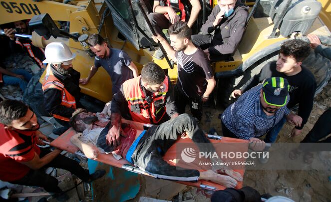 Спасатели извлекают тело погибшего из под завалов разрушенного в результате бомбардировки здания в секторе Газа. Ситуация на границе Израиля и сектора Газа обострилась вечером 10 мая. Столкновения мусульман с израильской полицией, начавшиеся после выселения из квартала Шейх-Джаррах в Восточном Иерусалиме нескольких палестинских семей, переросли в военные действия. Место: Палестина, Газа. Автор: Ахмед Закоут/РИА Новости. Ситуация в Палестине в связи с обострением палестино-израильского конфликта