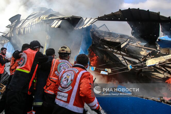 Члены Палестинской гражданской обороны тушат пожар на заводе по производству пенопласта в секторе Газа. Ситуация на границе Израиля и сектора Газа обострилась вечером 10 мая. Столкновения мусульман с израильской полицией, начавшиеся после выселения из квартала Шейх-Джаррах в Восточном Иерусалиме нескольких палестинских семей, переросли в военные действия. Место: Палестина, Газа. Автор: Ахмед Закоут/РИА Новости. Ситуация в Палестине в связи с обострением палестино-израильского конфликта